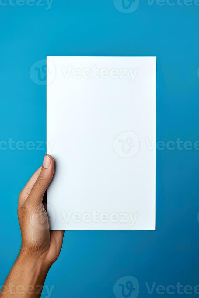 A human hand holding a blank sheet of white paper or card isolated on blue background. ai generated photo
