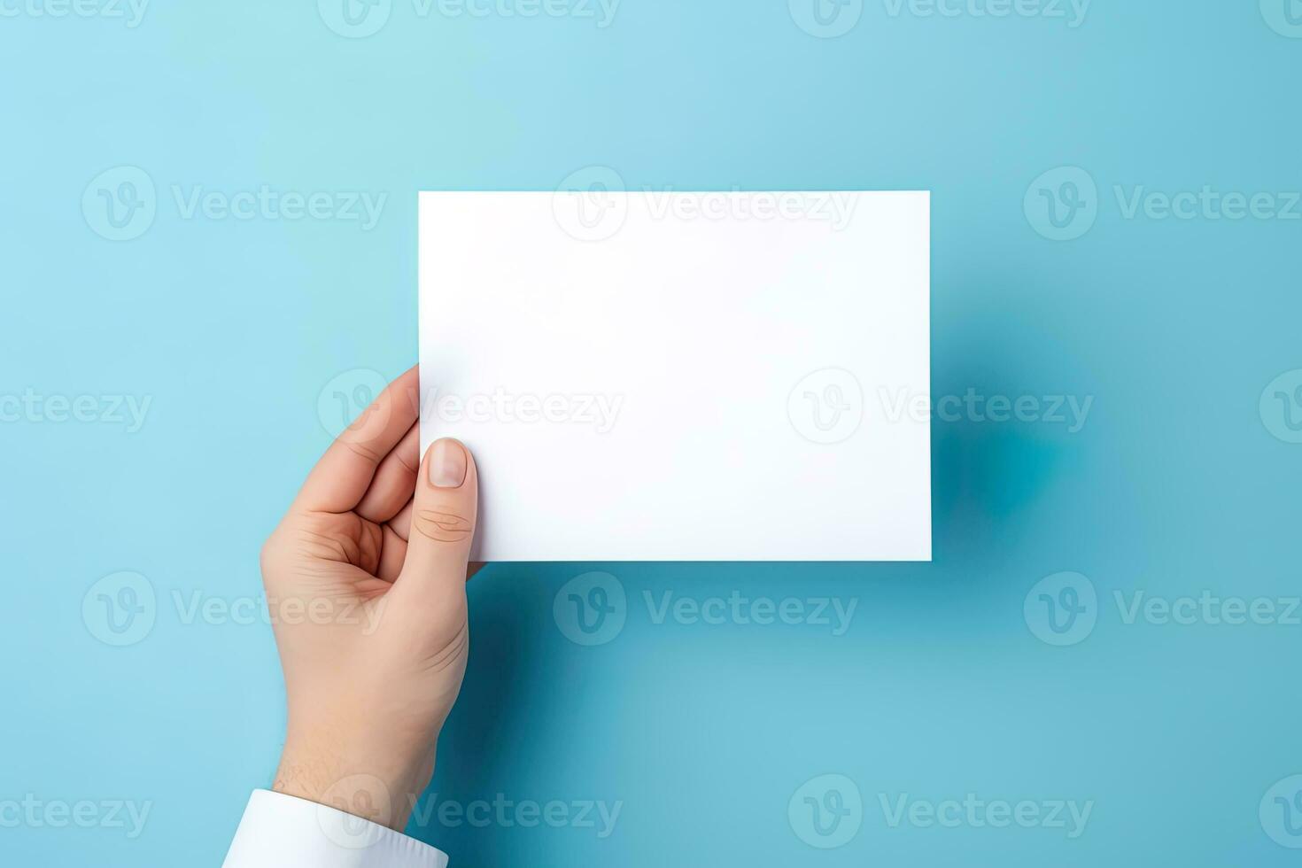 A human hand holding a blank sheet of white paper or card isolated on blue background. ai generated photo