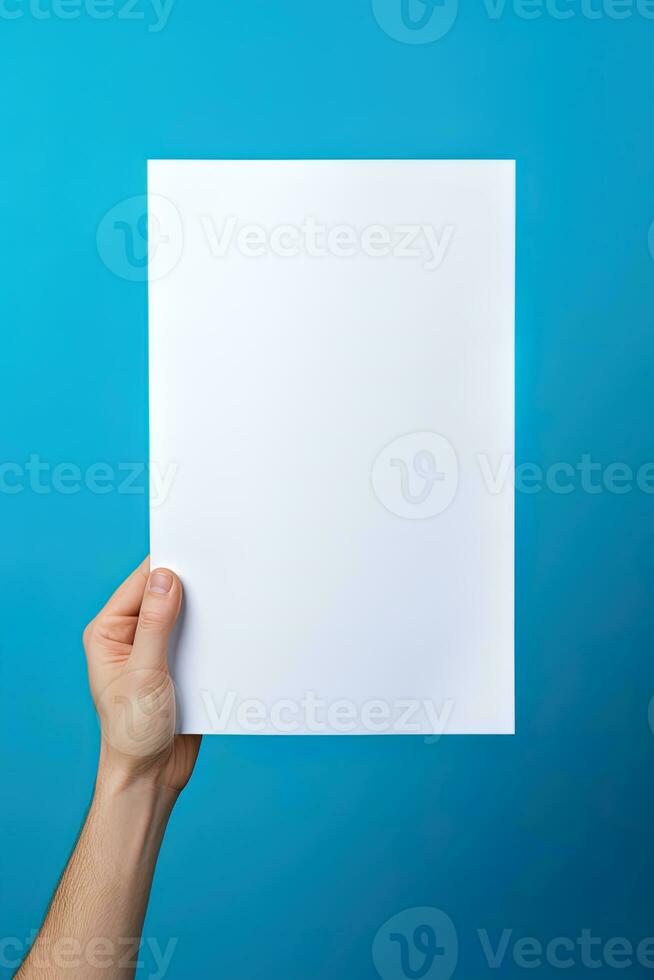 A human hand holding a blank sheet of white paper or card isolated on blue background. ai generated photo