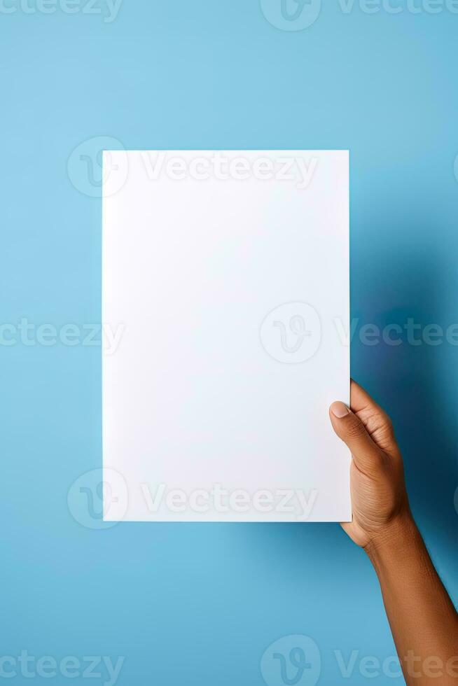 A human hand holding a blank sheet of white paper or card isolated on blue background. ai generated photo