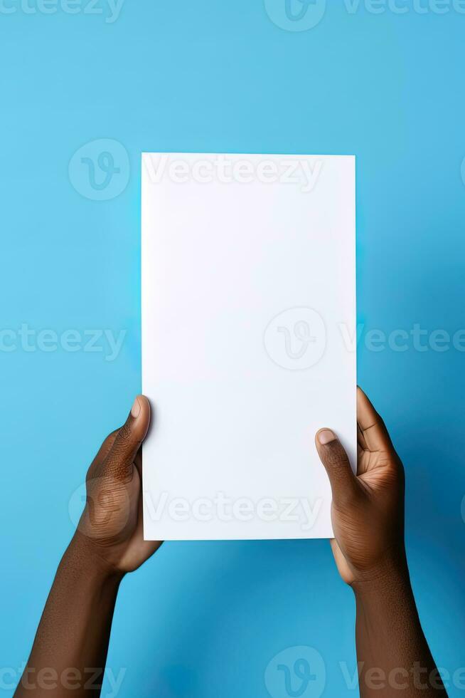 A human hand holding a blank sheet of white paper or card isolated on blue background. ai generated photo