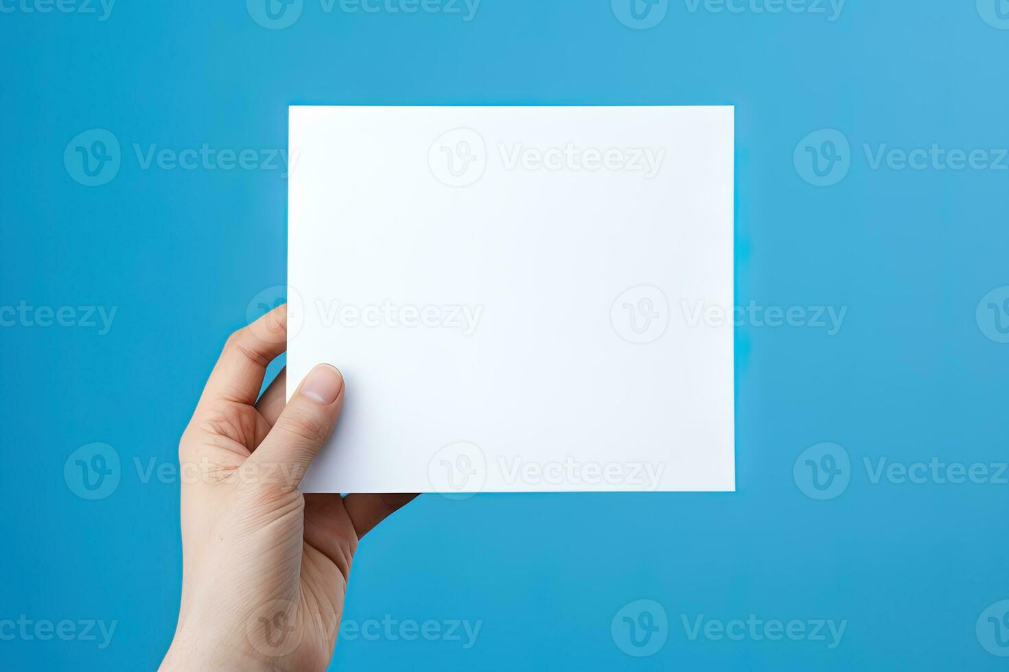 A human hand holding a blank sheet of white paper or card isolated on blue background. ai generated photo