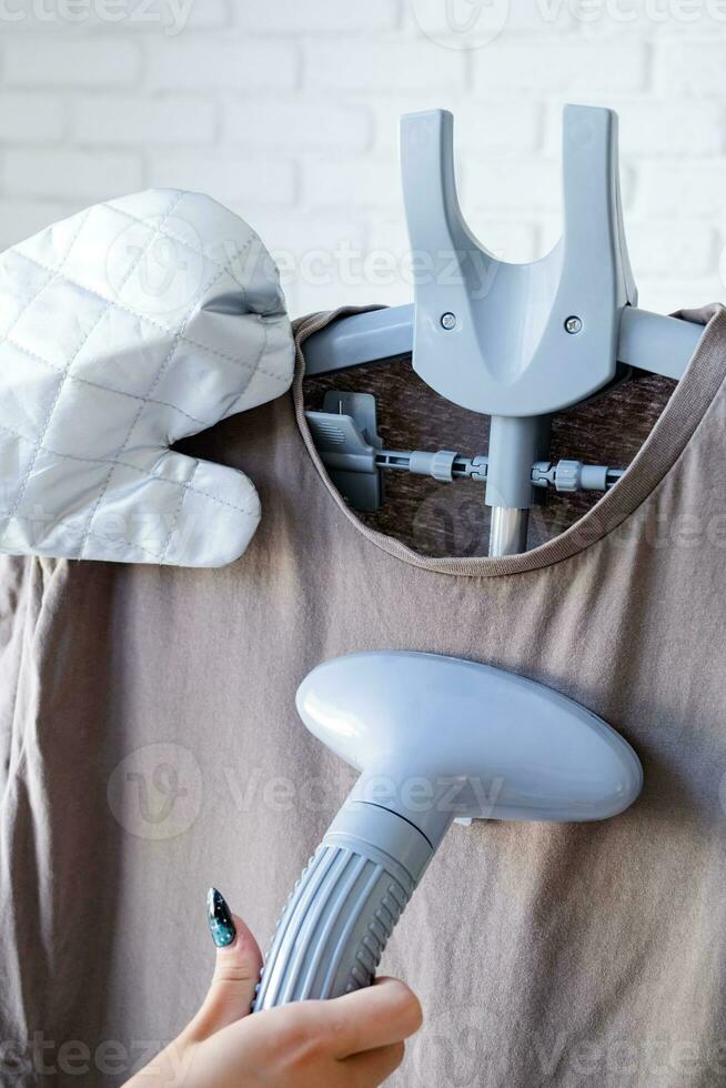 Close up of female hand with vertical steamer and tshirt photo