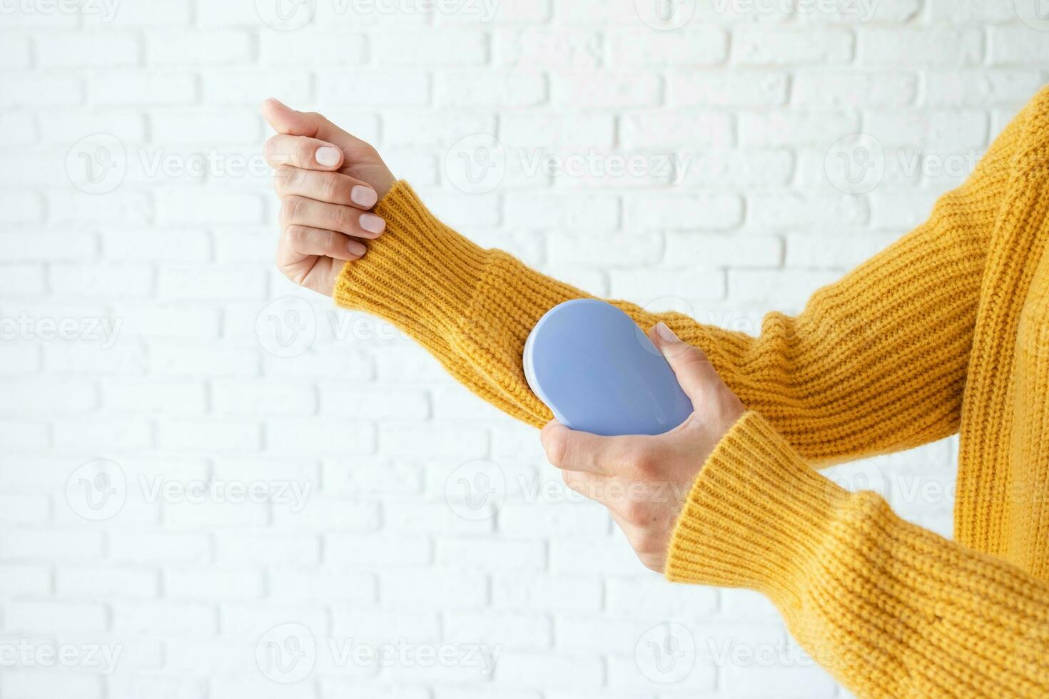 woman in yellow sweater using fabric pills removing tool photo