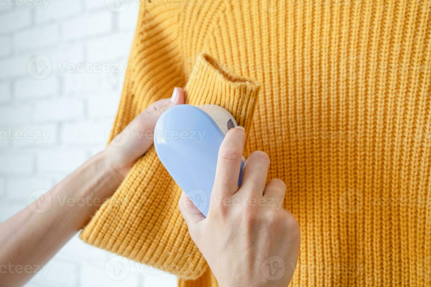 woman in yellow sweater using fabric pills removing tool photo