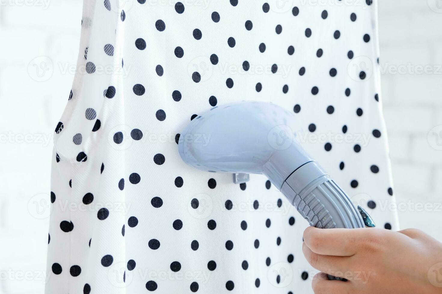 Close up of female hand with vertical steamer and summer dress photo