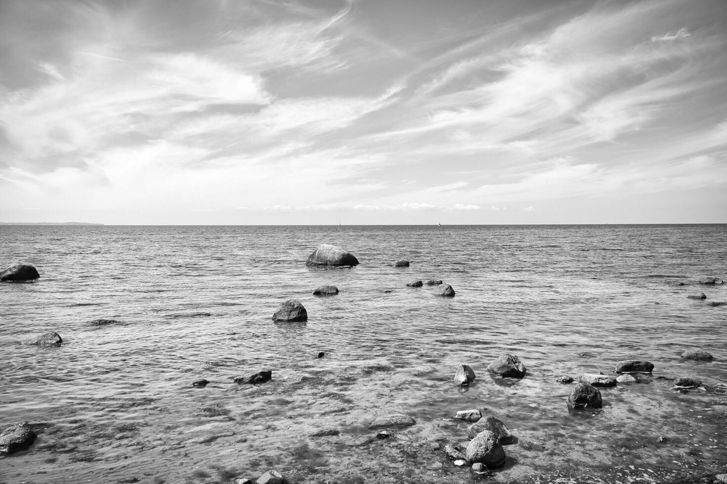 Stones and rocks on the Baltic coast in the sea in black and white. Landscape shot photo