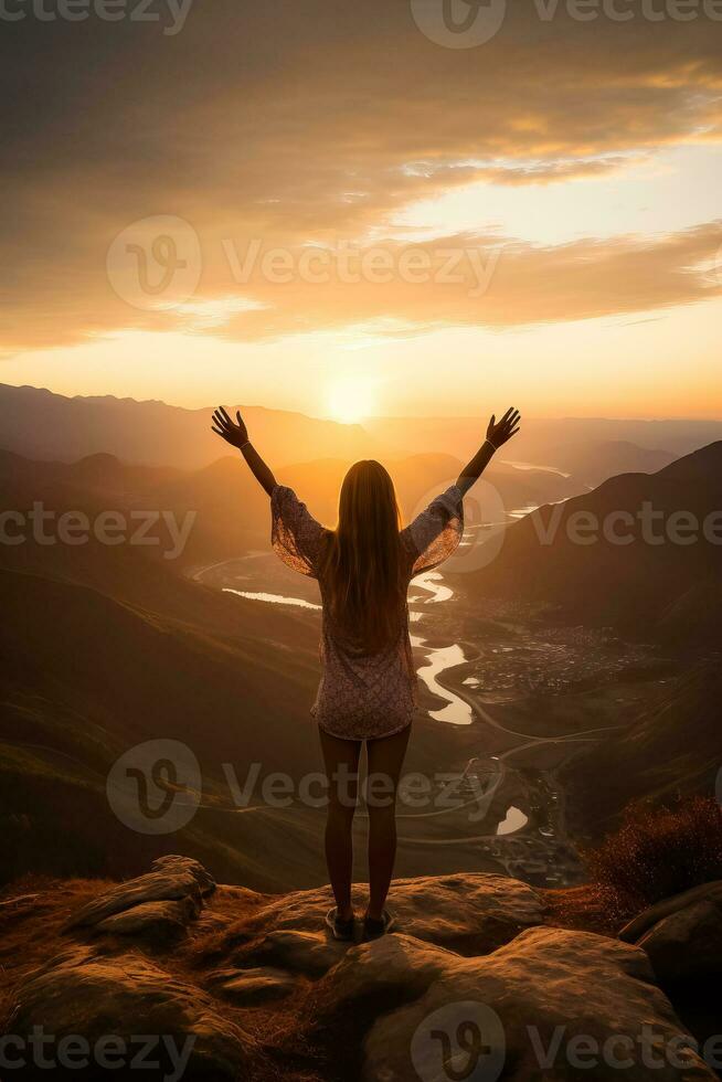 Young woman reaching for mountains at sunset surrounded by a beautiful landscape photo