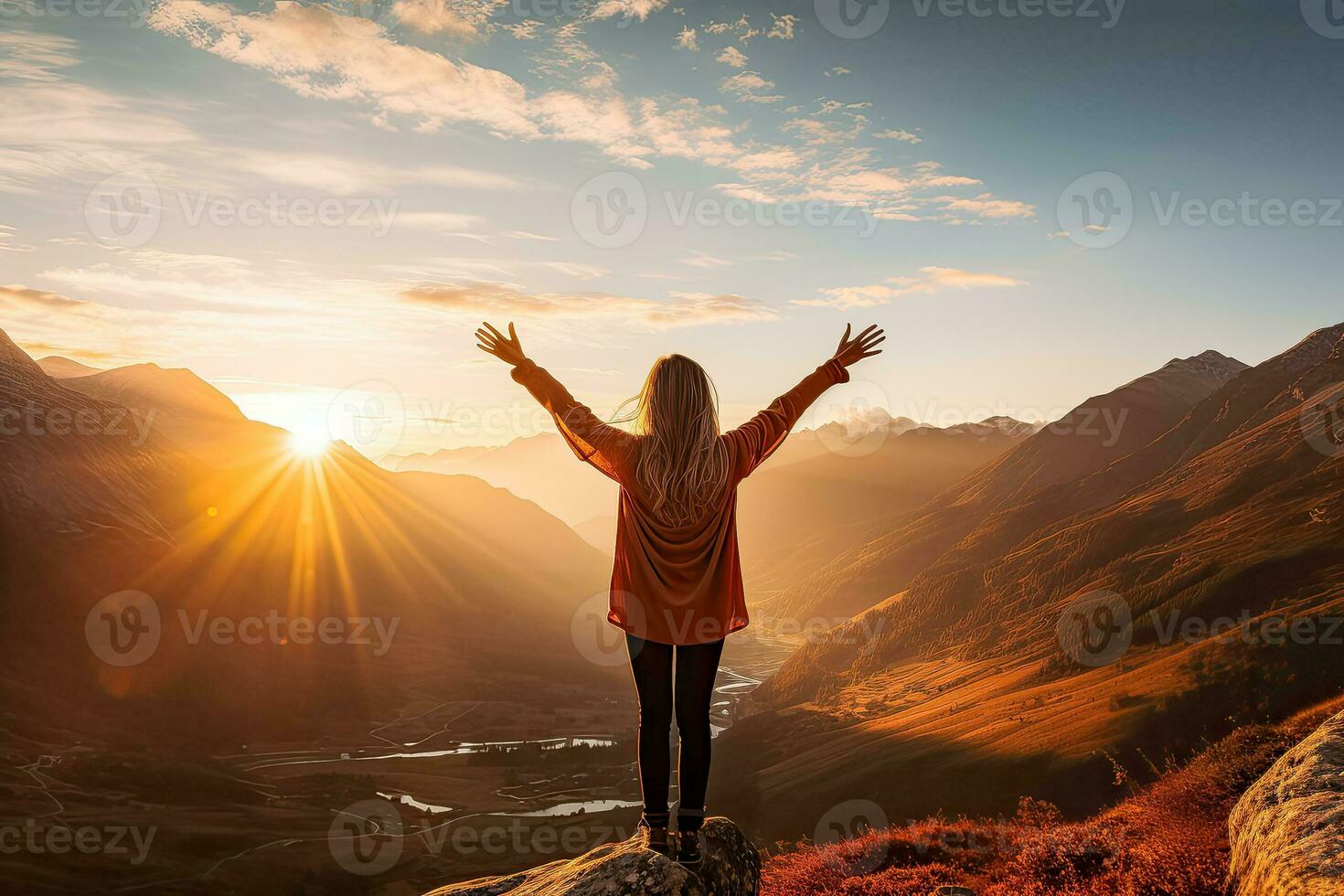 Young woman reaching for mountains at sunset surrounded by a beautiful landscape photo