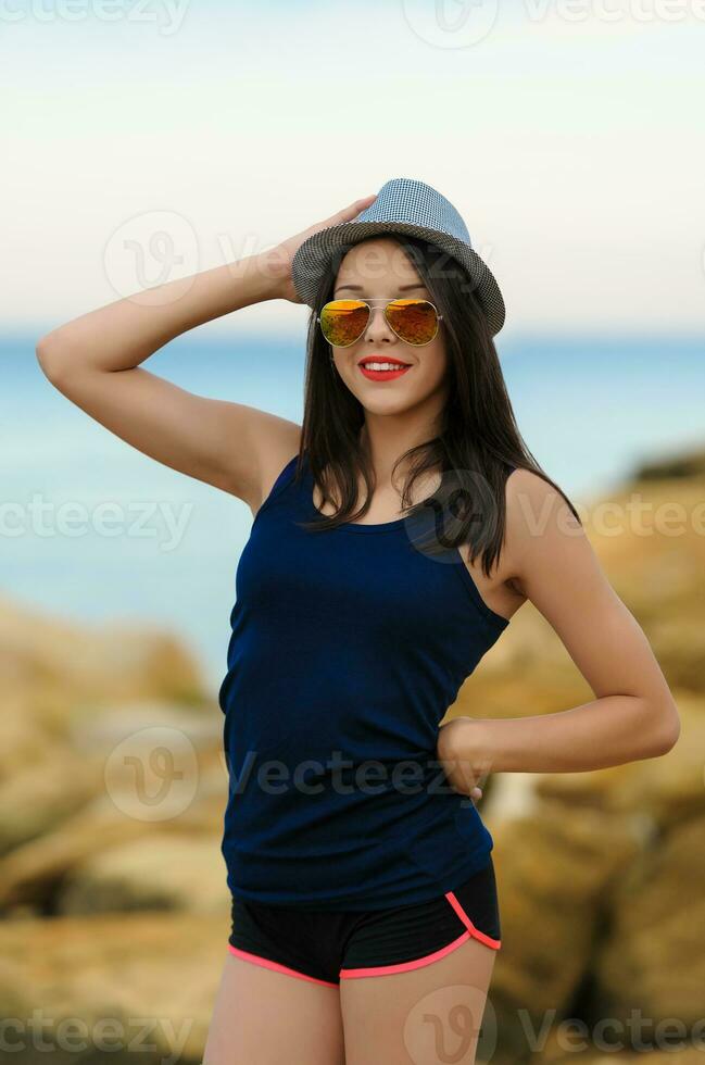 joven sonriente niña en gris sombrero y Dom lentes foto