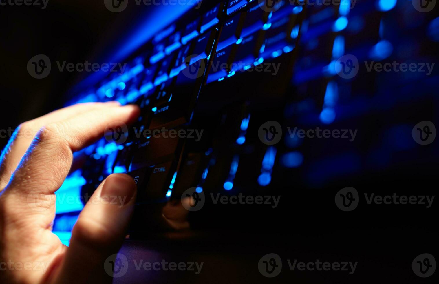 Man's hand typing on a blue keyboard. photo