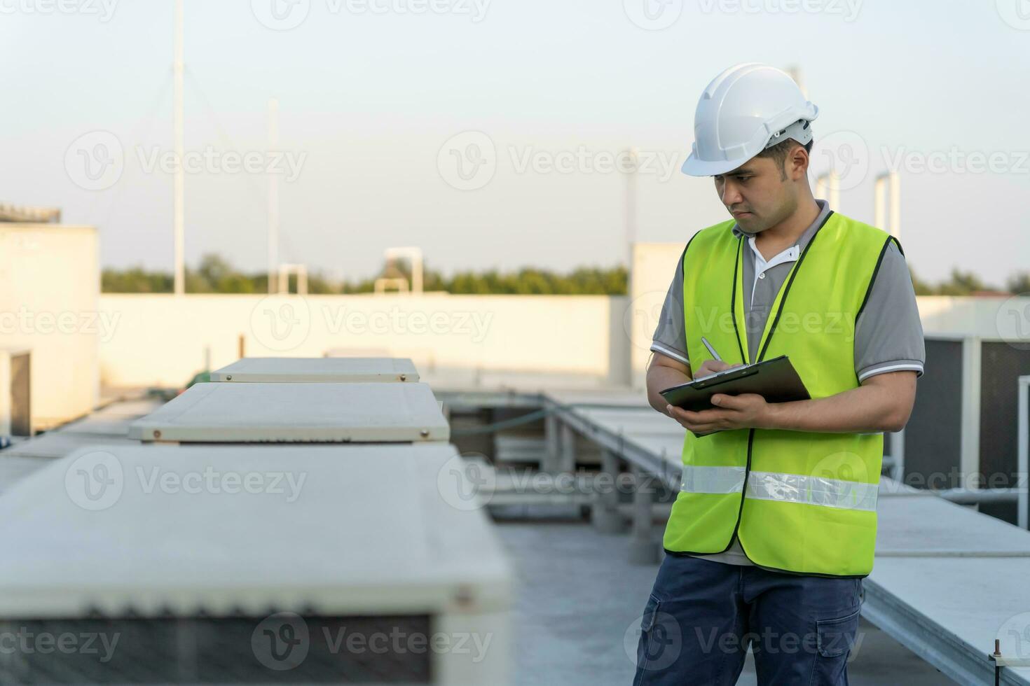 Asian maintenance engineer works on the roof of factory. contractor inspect compressor system and plans installation of air condition systems in construction. Checklist, inspector, control photo