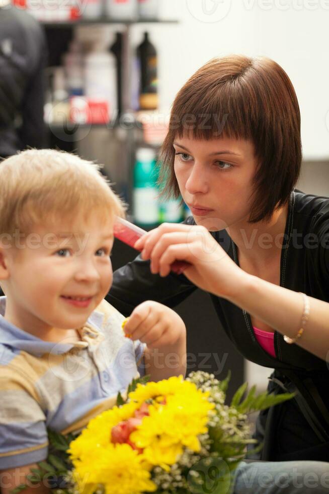 Young boy getting haircut from styist photo