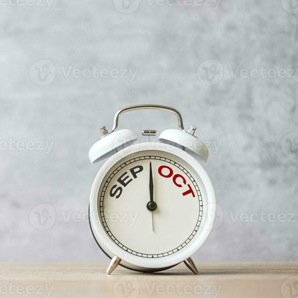 Hello October Changed from September  month with vintage alarm clock on table background. Calendar, Monthly, New Start, Resolution, Goals, Plan, Action and Mission Concept photo