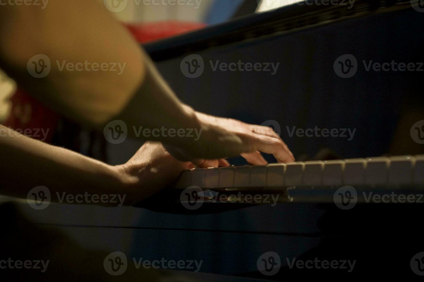 close-up on the hands of a woman playing the piano with music keys photo