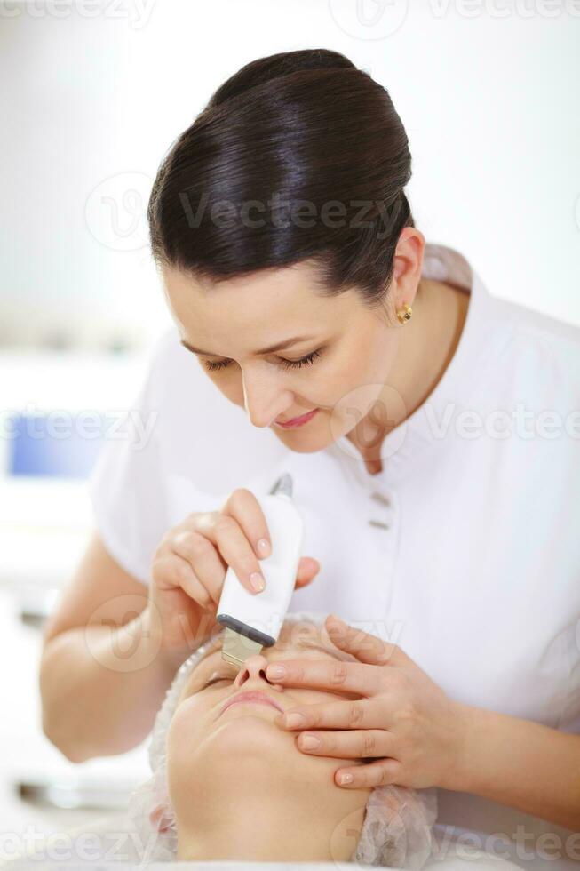 Cosmetician making ultrasonic face cleaning photo