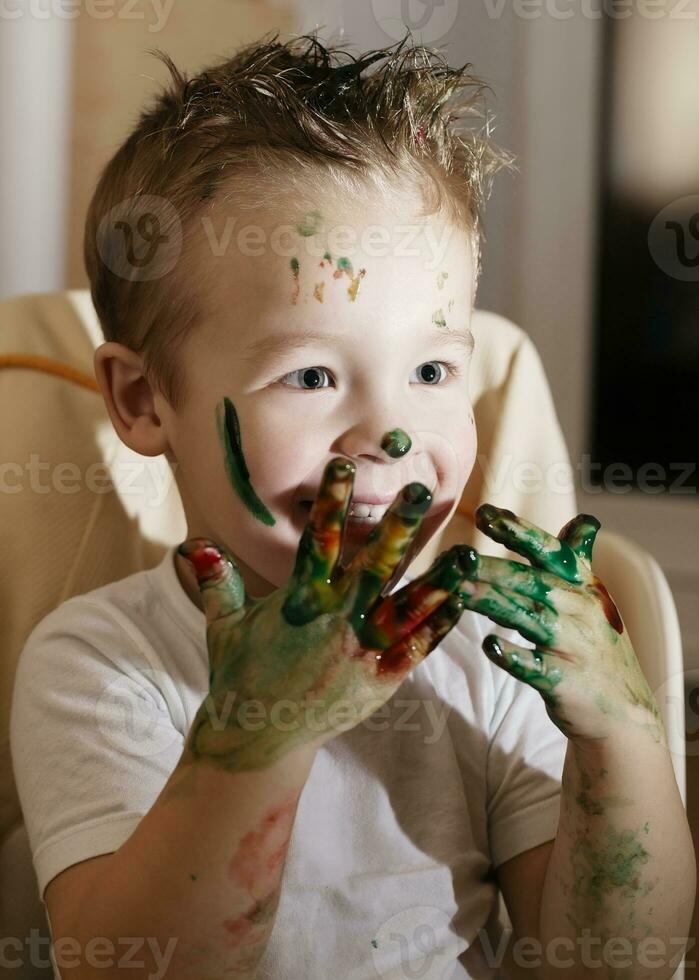 Excited little boy playing with finger paints photo