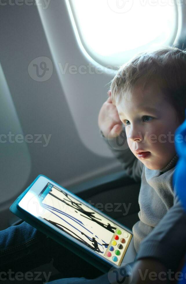 Little boy drawing on a tablet in an airplane photo