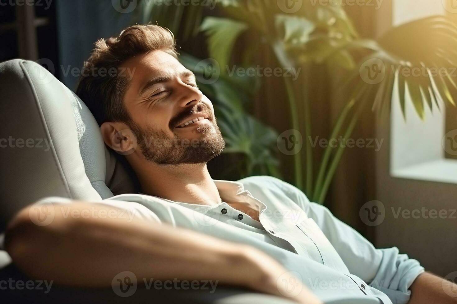 Satisfied handsome young man relaxing on the sofa at home, Smiling ...