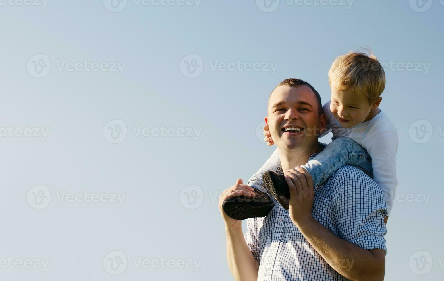 Young father giving his son a piggy back ride photo