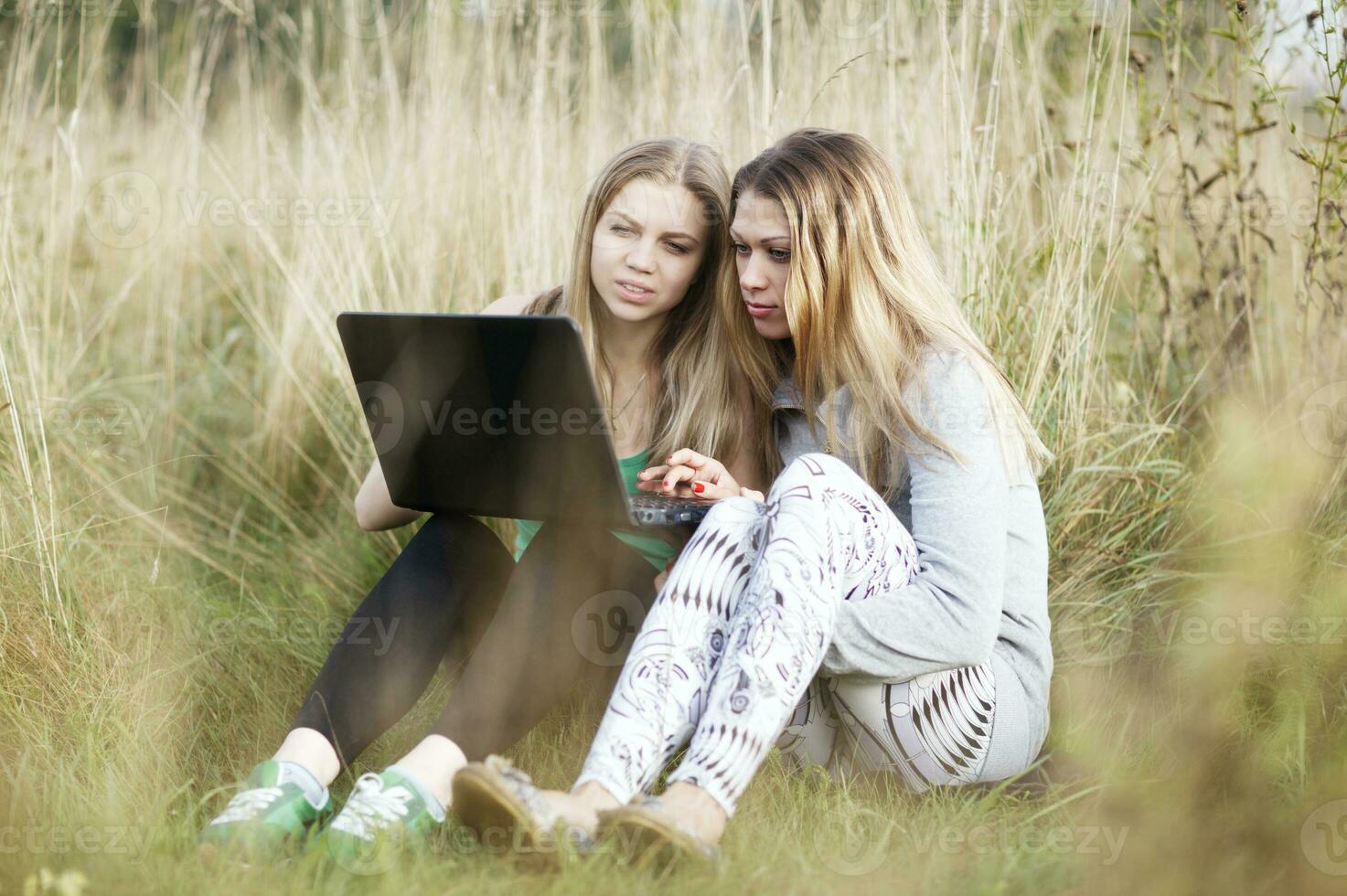 hembra amigos con ordenador portátil al aire libre foto