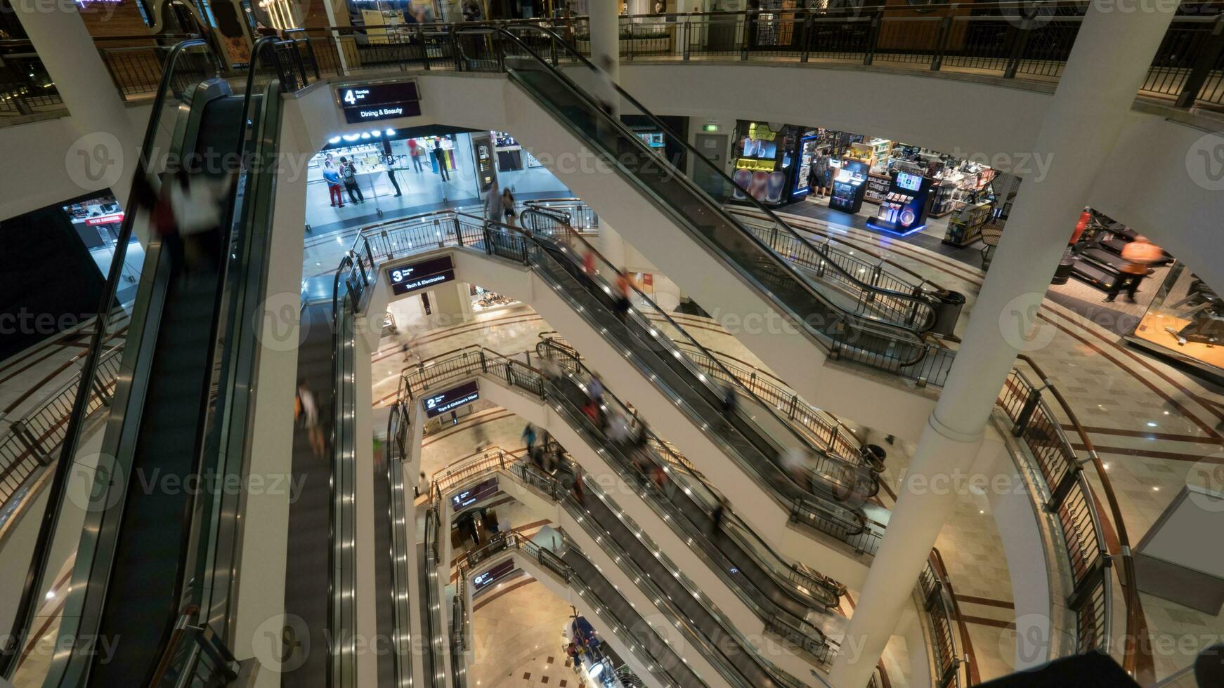 personas en escaleras mecánicas en de muchos pisos compras centro comercial foto