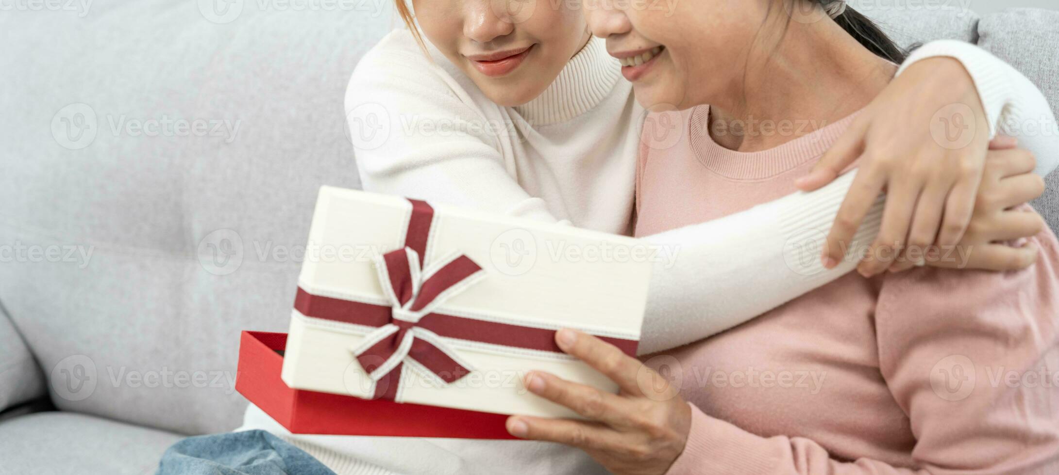 madre día, linda asiático adolescente niña dar regalo caja a maduro medio años mamá. amar, beso, cuidado, contento sonrisa disfrutar familia tiempo. celebrando especial ocasión, contento cumpleaños, contento nuevo años, alegre Navidad foto