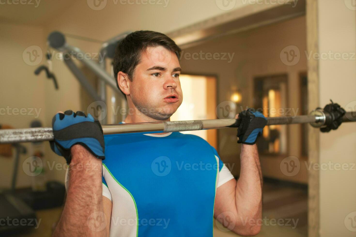 Strong young man exercising with barbell photo