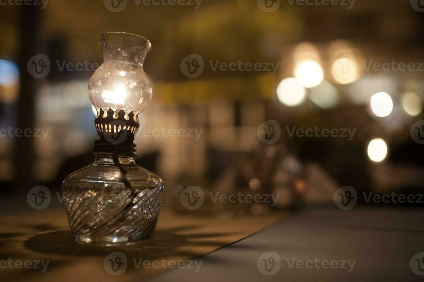 Antique oil lamp with dim light on table in cafe photo