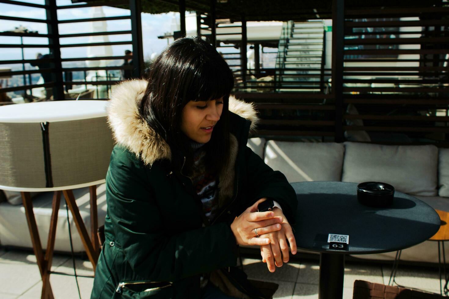 niña esperando mirando a el reloj a un mesa en el terraza de un bar foto