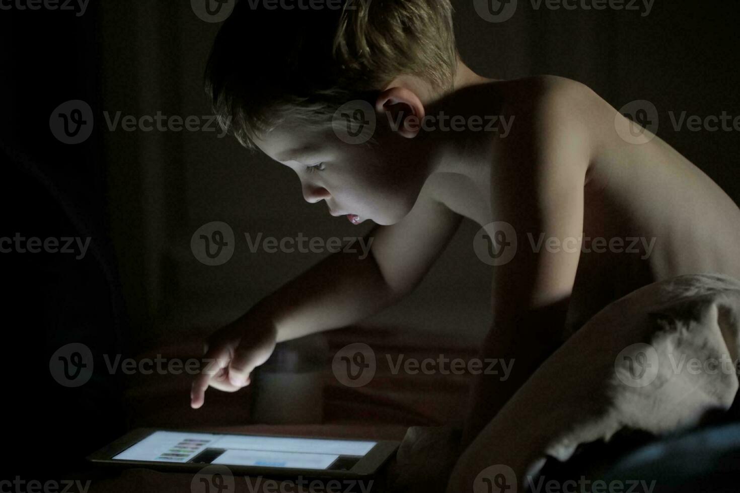 Little boy using tablet PC at night photo