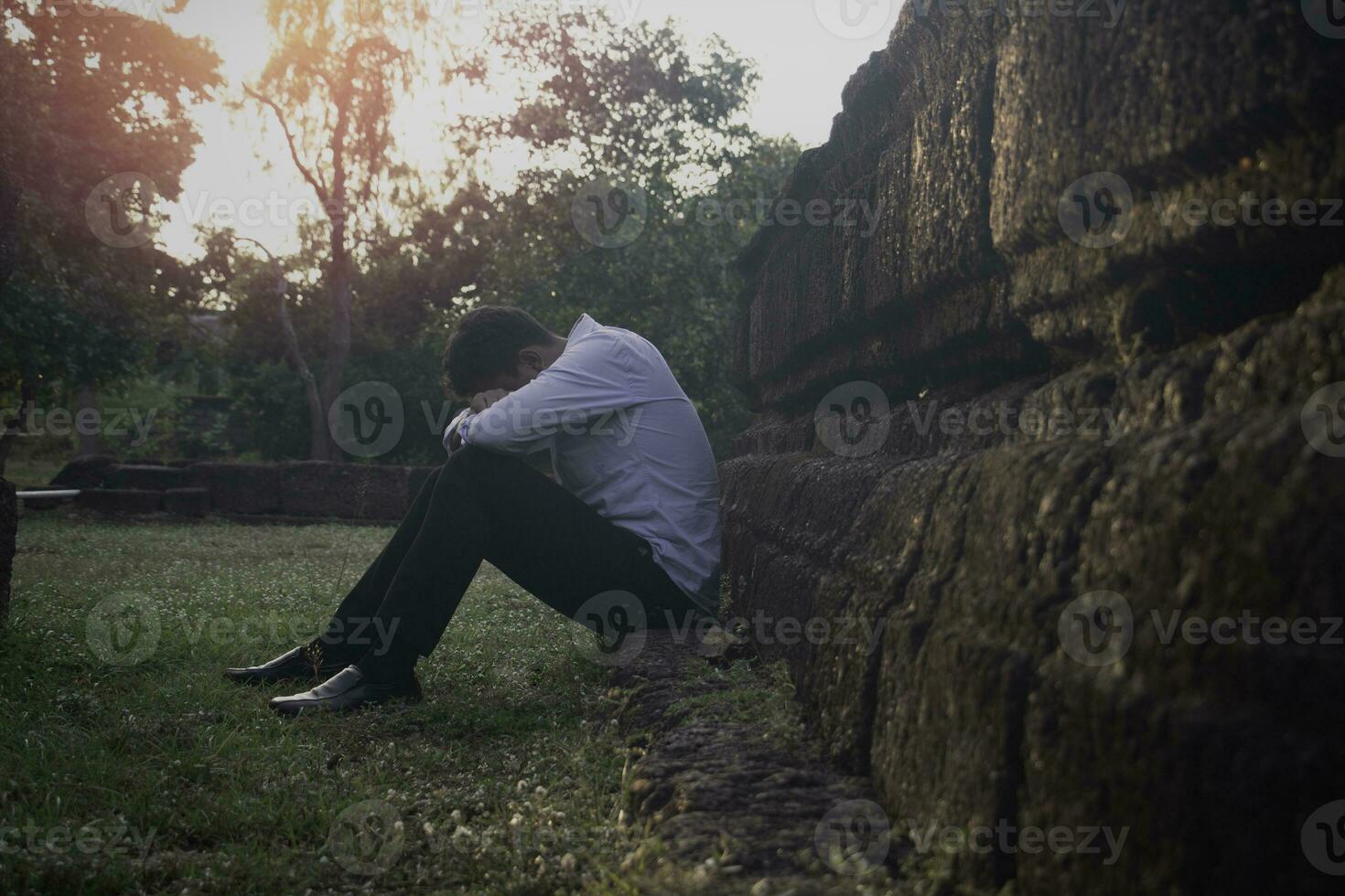 Asia you man sitting alone.He sitting alone beside old wall.man very sad and depressed.sad,alone,suicide,despair,sickness,photo health and disappointment concept. photo