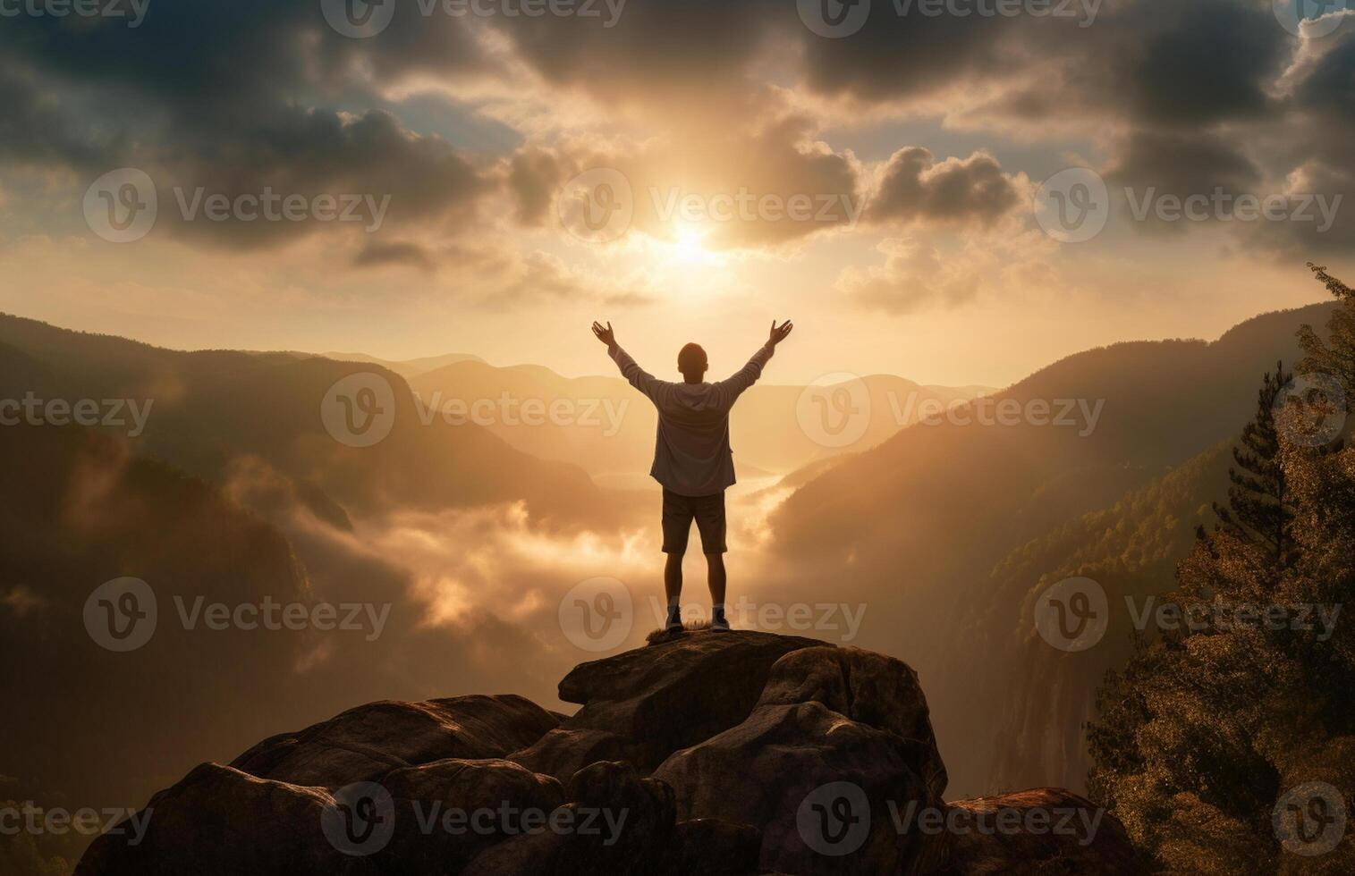 The silhouette of a tourist standing with his arms outstretched the golden glow of the morning sun on the mountaintop. Standing up to achieve success. photo