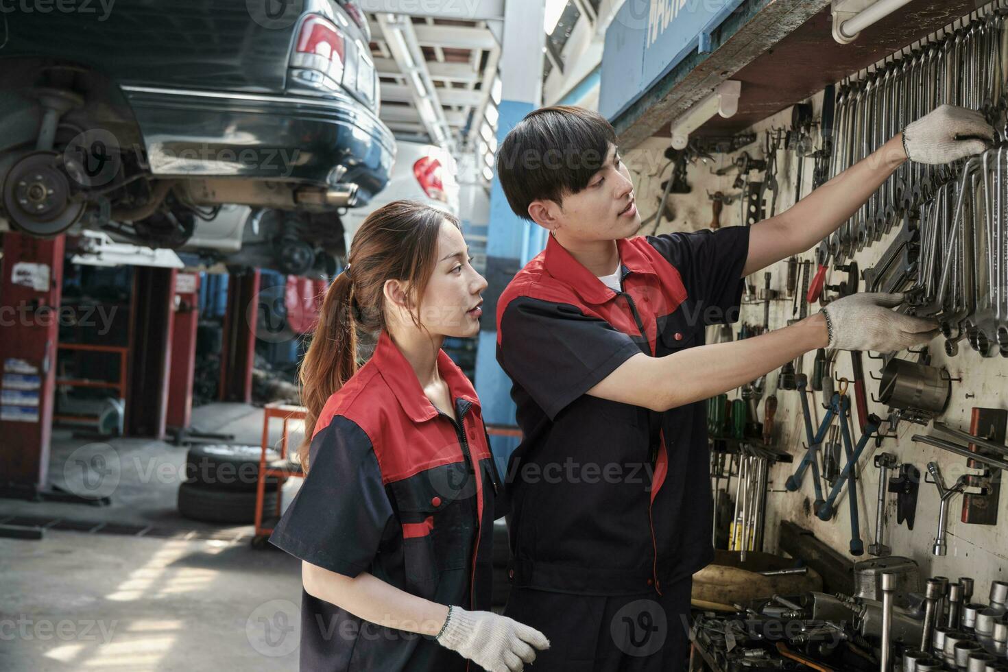 dos profesional asiático mecánico socios discutir mano herramientas y maquinaria para fijación trabajo a coche Servicio cochera, mantenimiento trabajos, y cheque y reparar ocupación en automotor industria negocio. foto