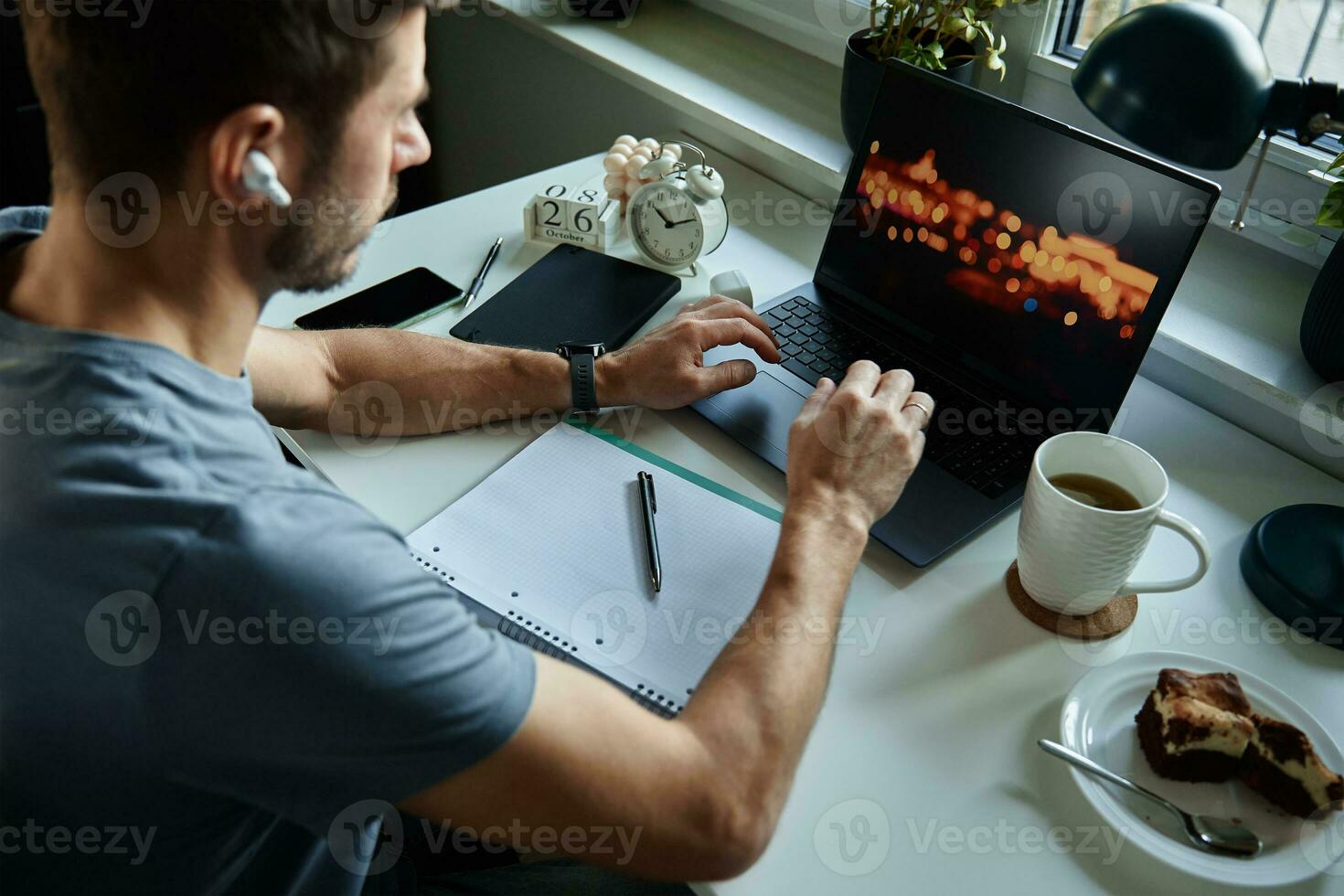 Man sitting at table by the window and using laptop photo