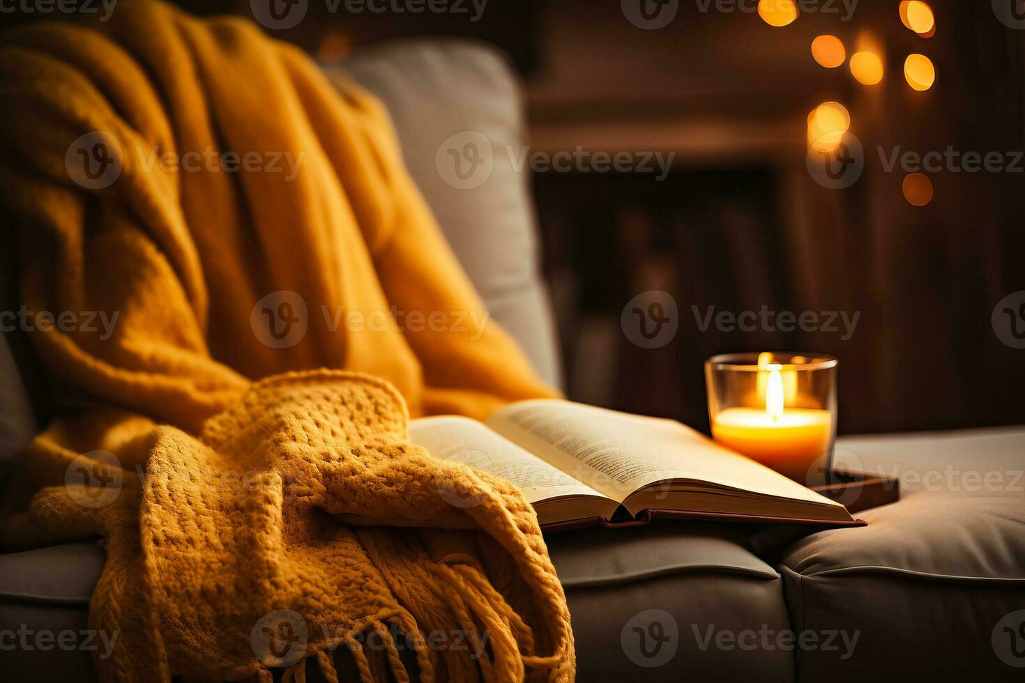 A young woman snuggles under a warm blanket sipping tea and getting lost in the pages of a captivating autumn read photo