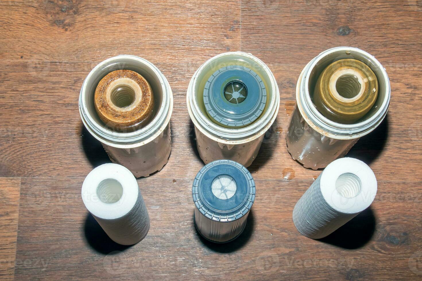 Used water filters with traces of dirt, clay and impurities and clean filters, prepared for replacement. Replacing multi-stage water filter cartridges. photo