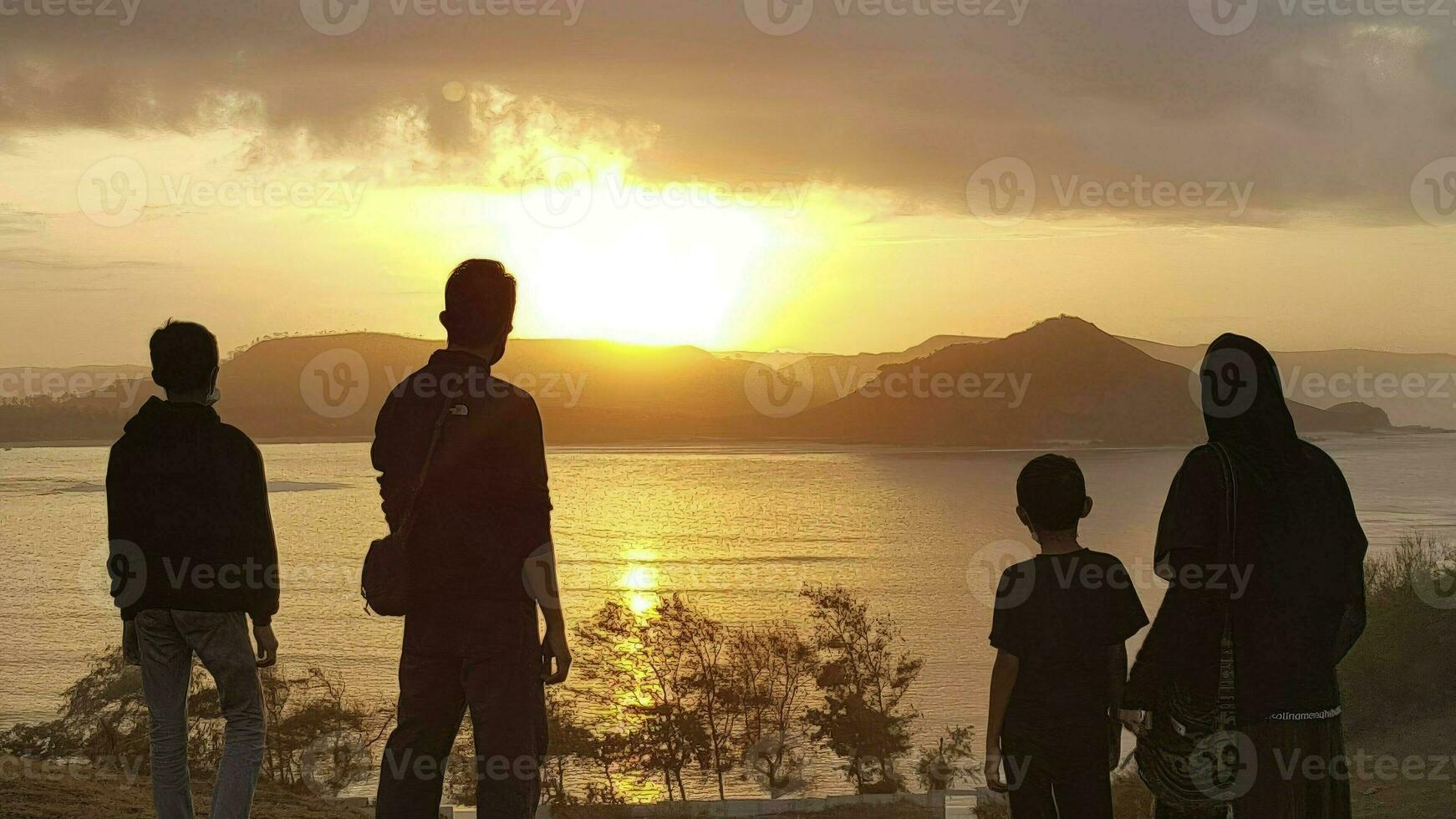 Silhouette of a happy family watching the sunset over the sea, Merese Hill, Lombok photo