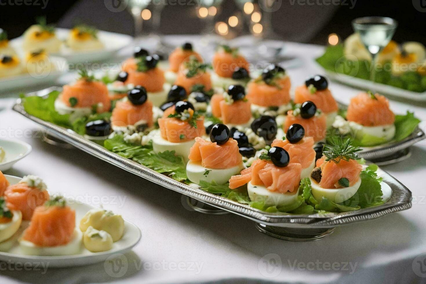 a stunning platter of appetizers on a silver platter, placed on a pristine white tablecloth. photo