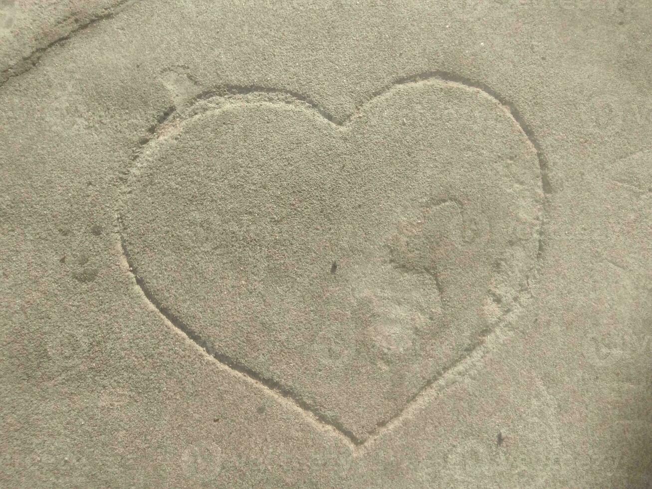 A heart is engraved in a big natural stone. The sign for love in a huge rock in the middle of a forest. Trees and green leaves in the background. A carved symbol in a block. photo