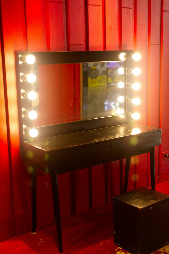 table with mirror and light for make up or dressing with red backgrounds photo