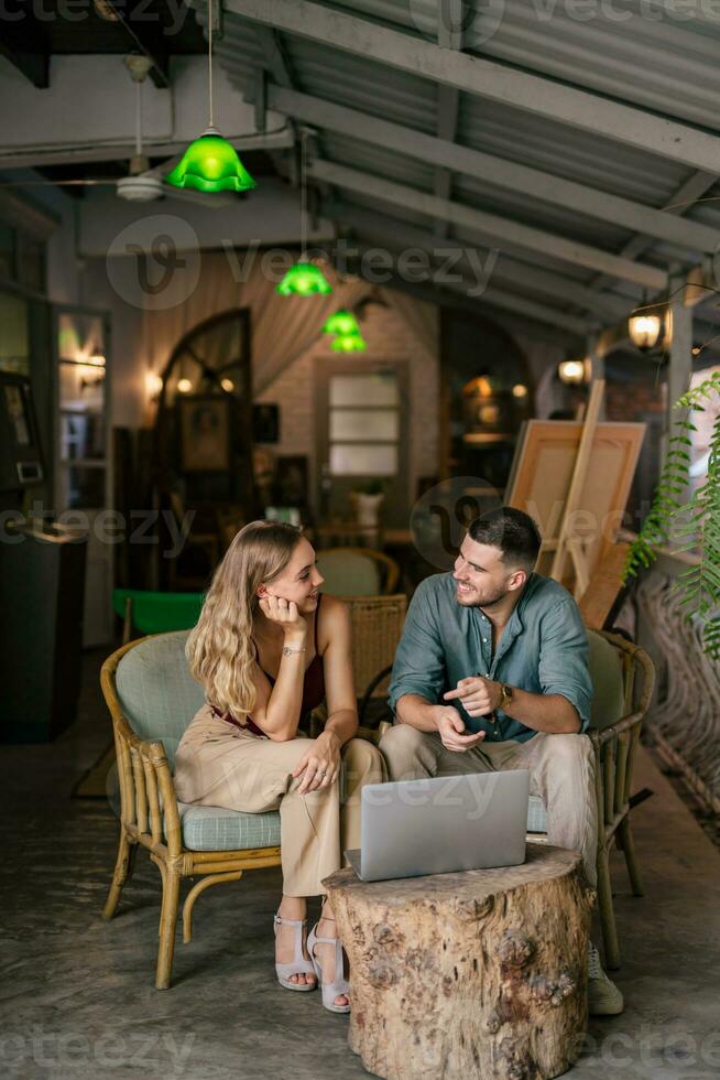 Young married couple sitting at the morning in they living room and using laptop. Couples sharing one idea together. photo