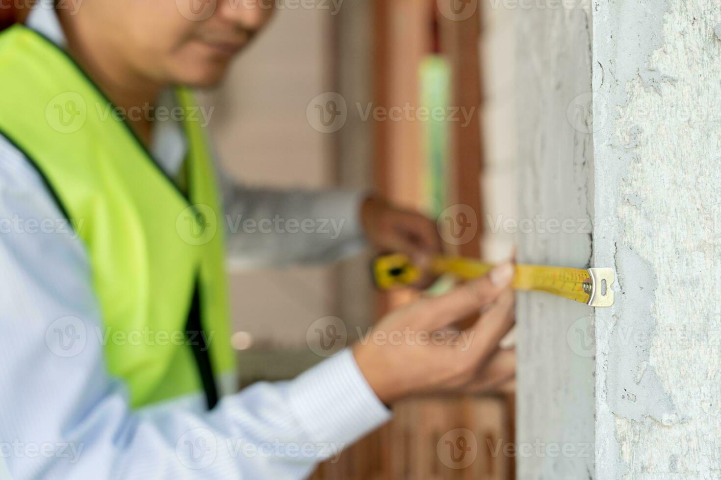 inspector or engineer is inspecting construction and quality assurance check dimension of house by using a tape measurement. Engineers or architects or contactor work to build the house before sell. photo