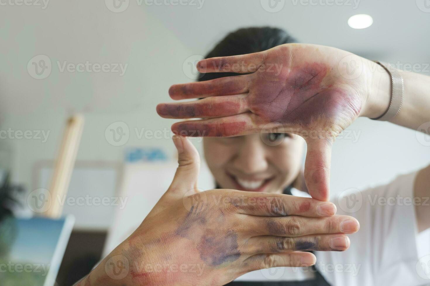 The artist creates a frame with her hands soiled with watercolor paints. photo