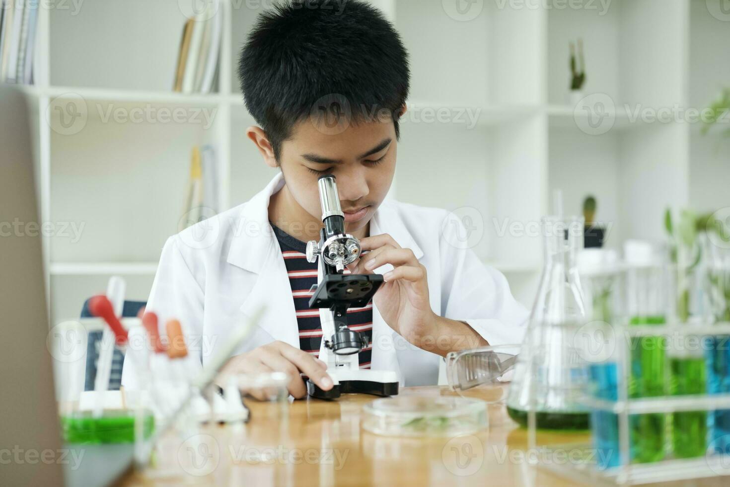 joven científico elemental colegial explora con microscopio foto