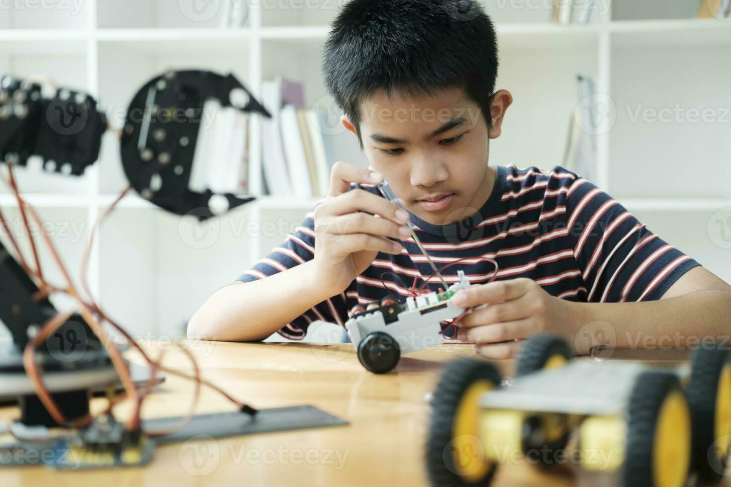 Asian teenager doing robot project in science classroom. technology of robotics programing and STEM education concept. photo