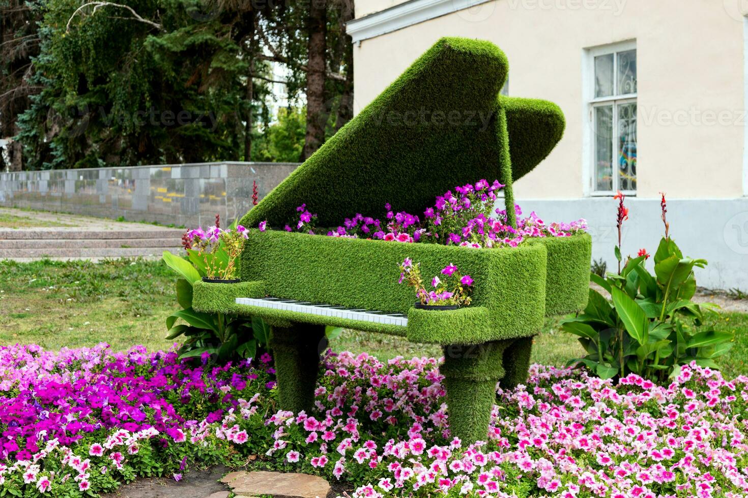Piano made of green grass in the garden of the house with a flower bed. photo