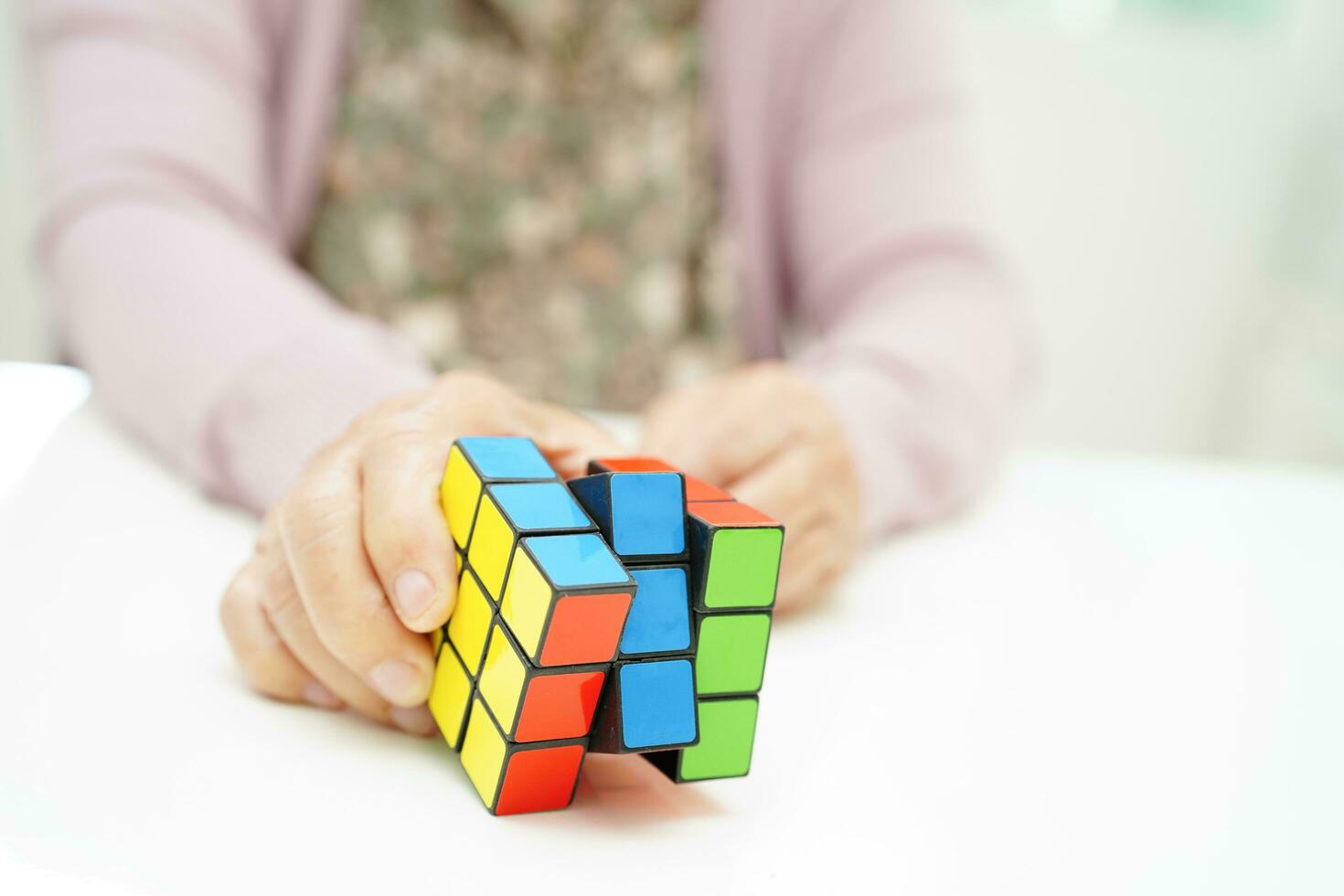 Bangkok, Thailand - May 15, 2022 Asian elderly woman playing Rubik cube game to practice brain training for help dementia prevention and Alzheimer disease. photo