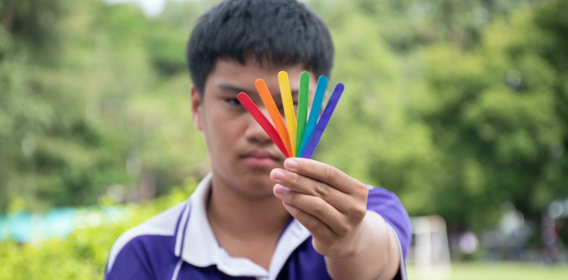 helado palos en arco iris colores participación en manos de asiático chico, suave y selectivo enfocar, concepto para vocación fuera todas personas a apoyo lgbt eventos y campañas alrededor el mundo. foto