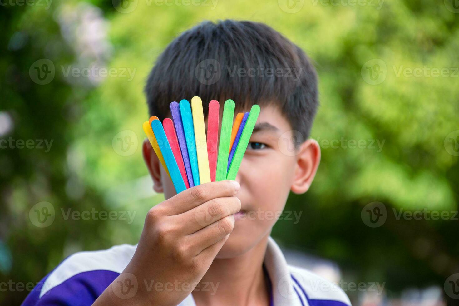 Ice-cream sticks in rainbow colours holding in hands of asian boy, soft and selective focus, concept for calling out all people to support LGBT events and campaigns around the world. photo